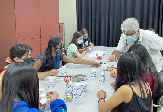 Picture of engineering faculty Mr. Shahram Marivani helps a Tech Trek student group build a robot out of paper cups, popsicle sticks, and a motor