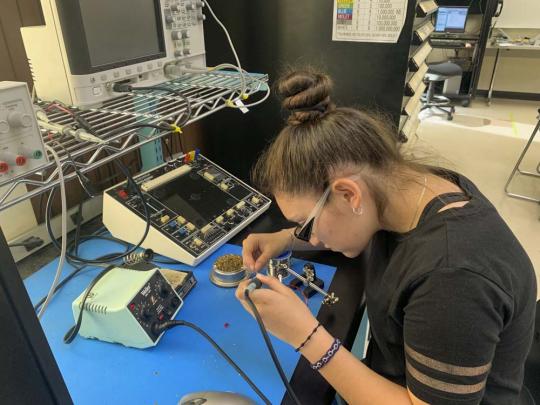 Picture of a high school student learning to solder in an engineering lab